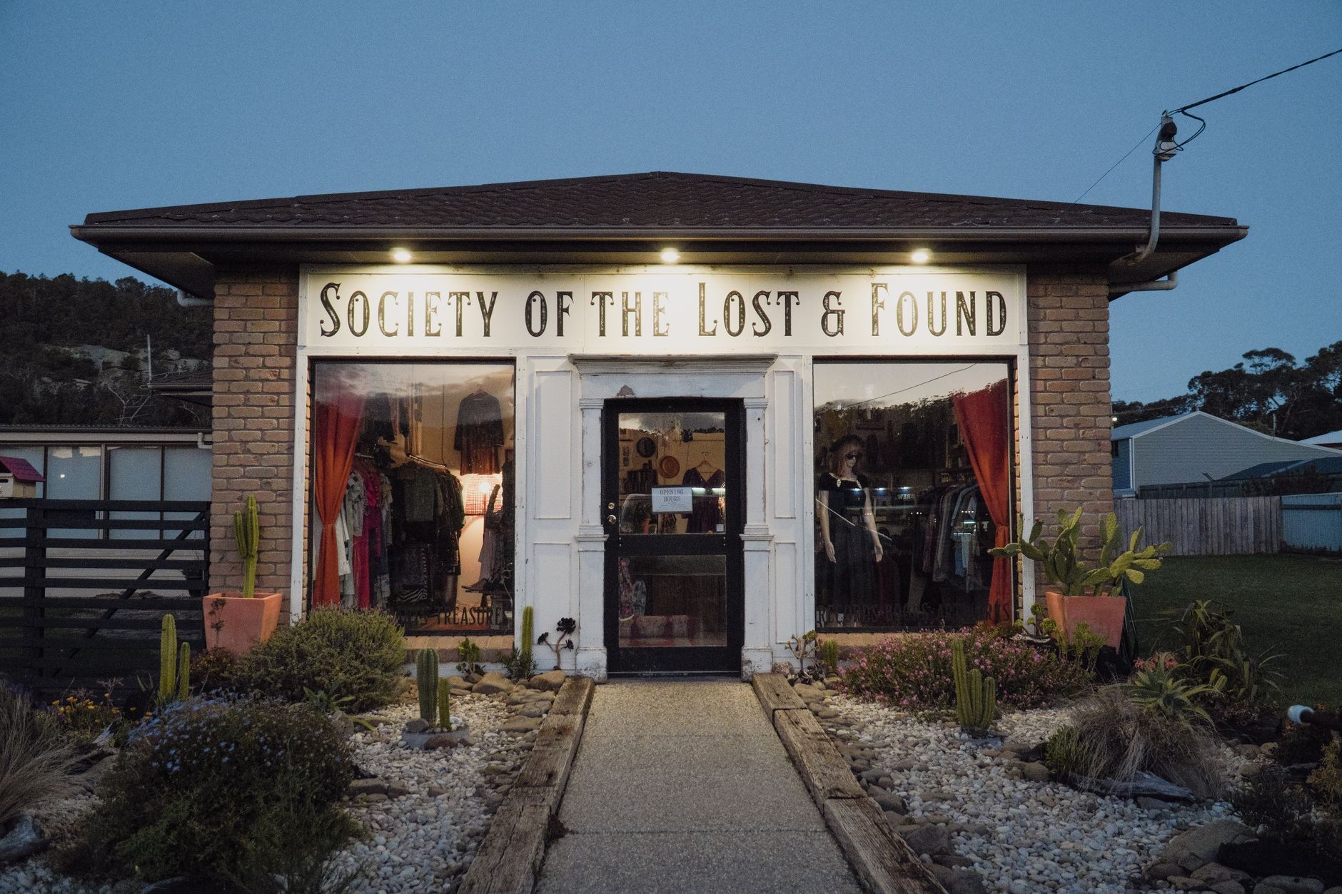 Inviting thrift store 'Society of the Lost & Found' in Bicheno, Tasmania at twilight.