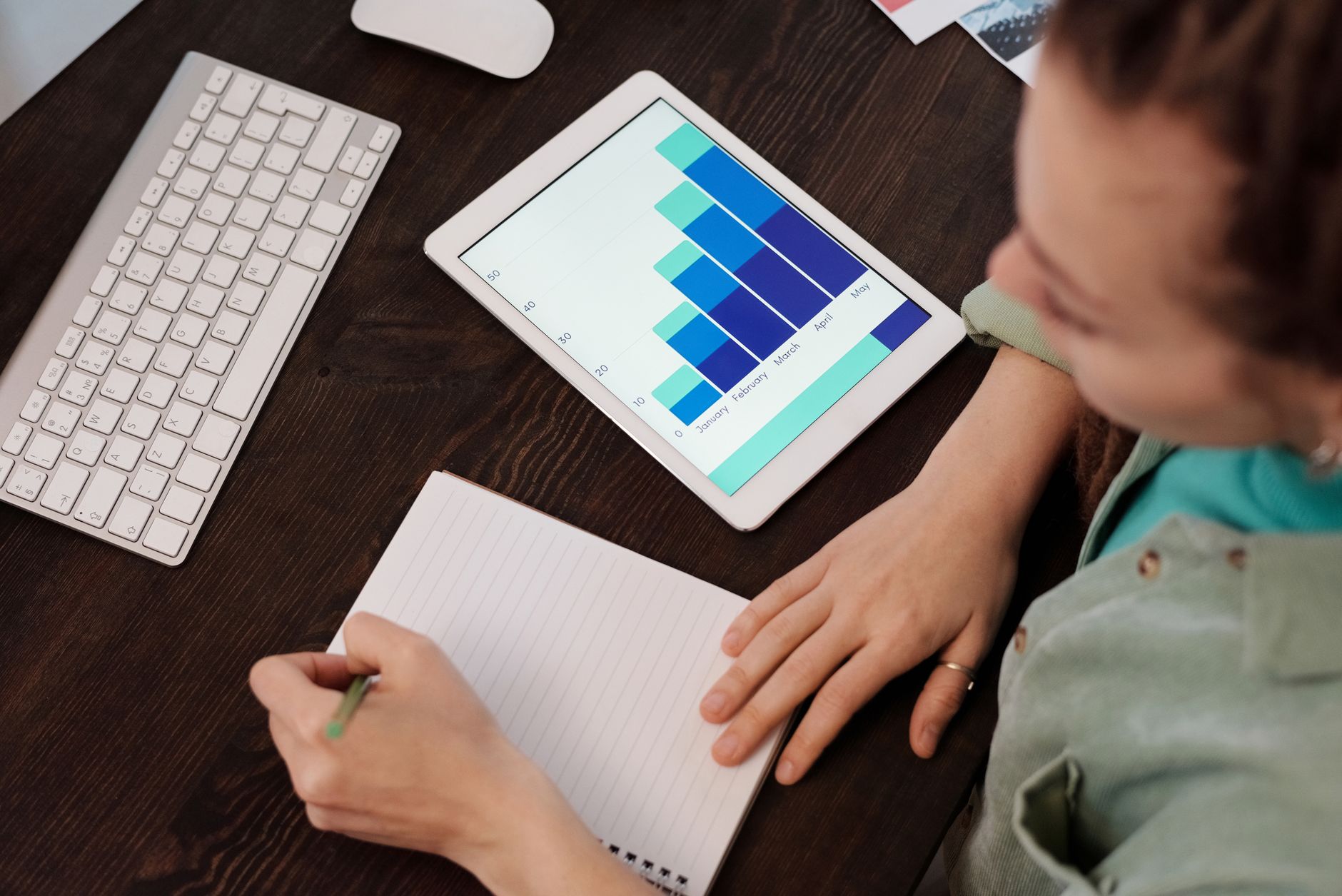 A woman taking notes while analyzing data on a tablet, ideal for business and technology themes.