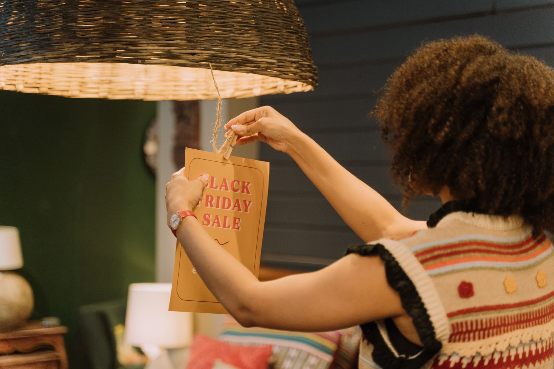 Back view of a woman hanging a Black Friday sale sign in a boutique store setting.