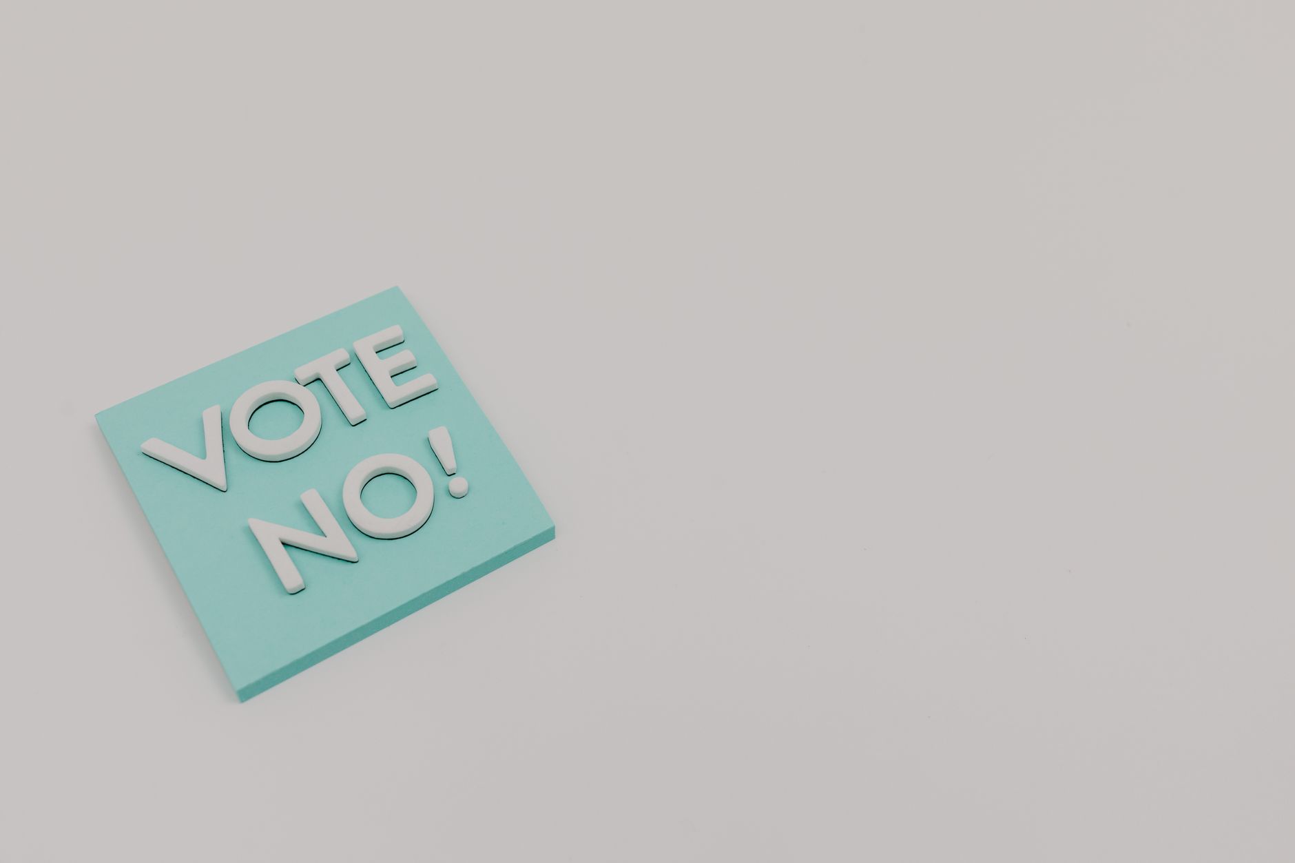 A blue sticky note displaying the message 'Vote No!' on a white surface, minimalistic and impactful.