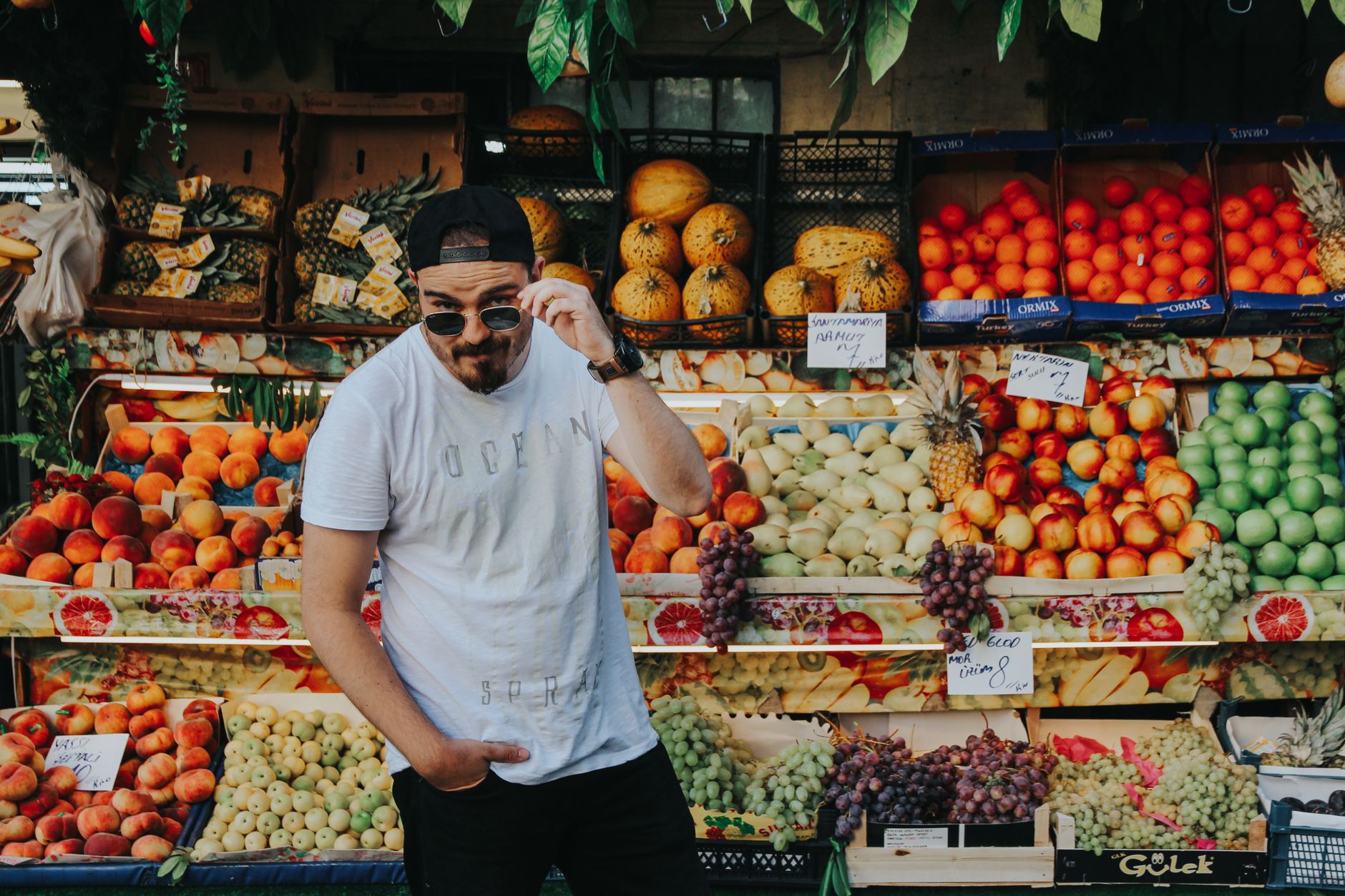 Explore a colorful fruit stall in Turkey's bustling street market, featuring fresh produce and a young vendor.